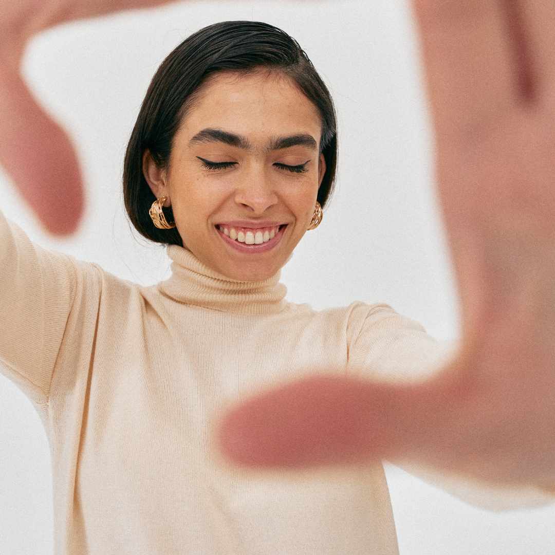 woman, smiling, holding her hands into the camera, closed eyes
